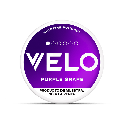 Envase redondo con una etiqueta en degradado morado en la que se lee VELO Mini Trial en texto blanco y en negrita. Encima pone bolsa de nicotina sin tabaco, y debajo, Producto de muestra. No a la venta. Marca: VELO.