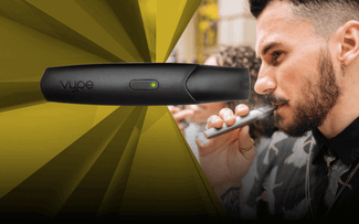 Un hombre con barba y tatuajes utiliza un dispositivo de vapeo, mientras se muestra un primer plano de un bolígrafo de vapeo Vype negro con una luz verde sobre un fondo amarillo y negro.